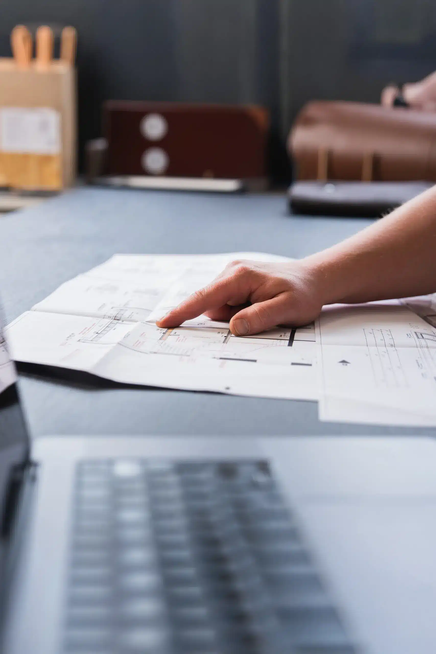 Detailaufnahme einer Hand, die auf eine technische Bauzeichnung zeigt, Symbol für Bauplanung bei Konstruktiv Plus in Bielefeld.
